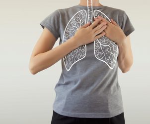 Kobieta trzyma dłonie w miejscu, w którym ma grafikę płuc. /Źródło: 123rf.com