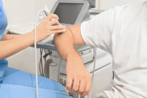 Lekarz przeprowadza pacjentowi badanie ultrasonograficzne doppler żył kończyny górnej. /Źródło: 123rf.com