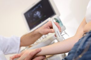 Doświadczony lekarz wykonuje pacjentowi badanie USG doppler za pomocą profesjonalnego sprzętu medycznego. /Źródło: 123rf.com