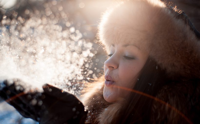 Kobieta w zimę zdmuchuje śnieg z rękawiczek. /Źródło: 123rf.com