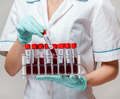 Pielęgniarka w medycznym stroju trzyma w dłoniach probówki wypełnione wcześniej pobraną krwią pacjentów. /Źródło: 123rf.com