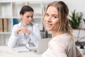 Młoda uśmiechnięta kobieta jest zadowolona z przeprowadzanej konsultacji lekarskiej. /Źródło: 123rf.com