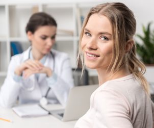 Młoda uśmiechnięta kobieta jest zadowolona z przeprowadzanej konsultacji lekarskiej. /Źródło: 123rf.com