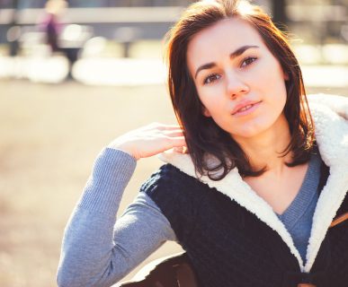 Młoda kobieta siedzi na ławce w parku w słoneczną pogodę. /Źródło: 123rf.com