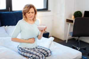 Kobieta podczas menopauzy trzyma się za bolący brzuch. /Źródło: 123rf.com