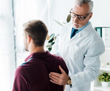 Doświadczony lekarz bada mężczyźnie plecy na konsultacji, w celu wykluczenia wad postawy. /Źródło: 123rf.com