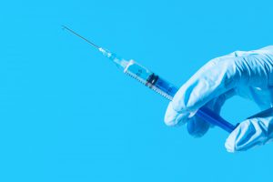 Lekarz trzyma w dłoni odzianej w sterylną rękawiczkę, strzykawkę ze szczepionką. /Źródło: 123rf.com