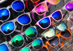 Różnokolorowe okulary przeciwsłoneczne ułożone na wystawie sklepowej. /Źródło: 123rf.com