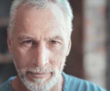 Starszy, zadbany mężczyzna z siwymi włosami patrzy w obiektyw. /Źródło: 123rf.com