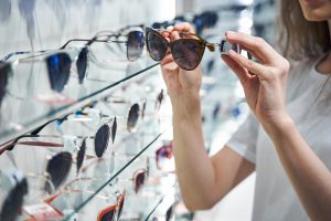Młoda kobieta wybiera okulary słoneczne w salonie optycznym. /Źródło: 123rf.com