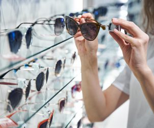 Młoda kobieta wybiera okulary słoneczne w salonie optycznym. /Źródło: 123rf.com
