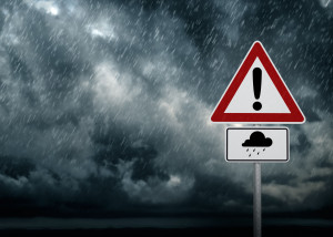 Znak drogowy ostrzegający przed opadami i burzą, na tle niesprzyjających warunków atmosferycznych. /Źródło: 123rf.com