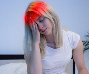 Dziewczyna z migreną trzyma się za głowę. /Źródło: 123rf.com
