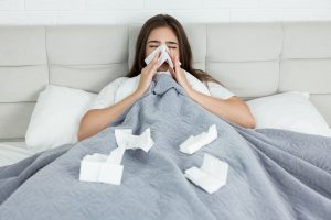 Kobieta leży chora w łóżku i wyciera nos w chusteczki. /Źródło: 123rf.com