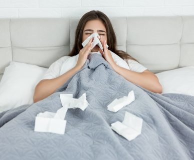 Kobieta leży chora w łóżku i wyciera nos w chusteczki. /Źródło: 123rf.com