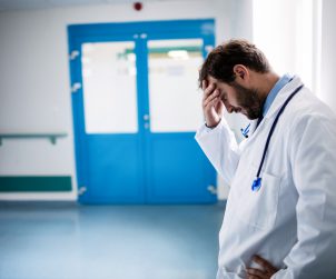 Niezadowolony lekarz trzyma się za głowę jako gest wyczerpania. /Źródło: 123rf.com
