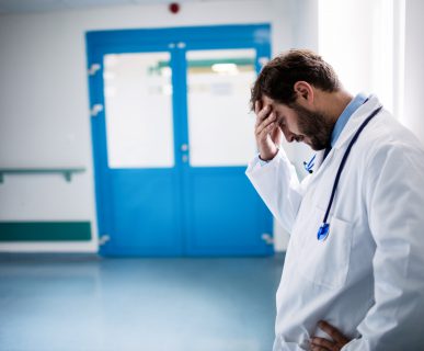 Niezadowolony lekarz trzyma się za głowę jako gest wyczerpania. /Źródło: 123rf.com