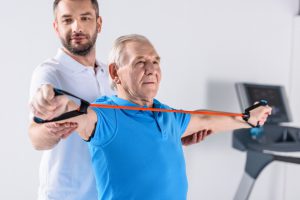Lekarz przeprowadza rehabilitacje starszemu mężczyźnie. /Źródło: 123rf.com