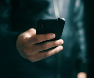 Mężczyzna sprawdza wiadomość SMS na telefonie. /Źródło: 123rf.com