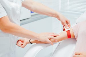 Pielęgniarka pobiera próbkę krwi od pacjenta z żyły u ręki. Źródło: 123rf.com