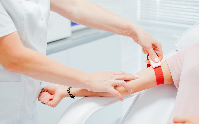 Pielęgniarka pobiera próbkę krwi od pacjenta z żyły u ręki. Źródło: 123rf.com