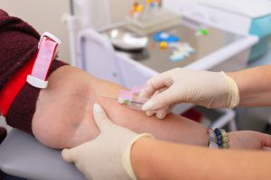 Pielęgniarka w białych rękawiczkach zamierza pobrać krew z żyły kobiety do analizy laboratoryjnej. Źródło: 123rf.com