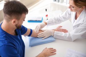 Pielęgniarka w sterylnych warunkach przygotowuje pacjenta do pobrania krwi w celu dalszej diagnostyki laboratoryjnej. Źródło 123rf.com