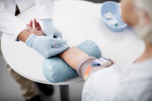 Pielęgniarz pobiera starszemu pacjentowi krew z żyły u ręki aby następnie poddać ją diagnostyce laboratoryjnej. Źródło: 123rf.com