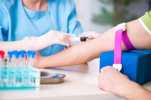 Pielęgniarka ubrana w sterylny, medyczny strój pobiera krew pacjentowi w celu diagnostyki i analizy laboratoryjnej. Źródło 123rf.com