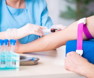 Pielęgniarka ubrana w sterylny, medyczny strój pobiera krew pacjentowi w celu diagnostyki i analizy laboratoryjnej. Źródło 123rf.com