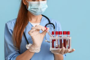 Pielęgniarka odziana w medyczny strój trzyma w dłoniach probówki wypełnione krwią pacjentów do celów dalszej diagnostyki laboratoryjnej. Źródło: 123rf.com