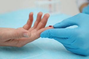 Pielęgniarka pobiera pacjentowi krew z palca w celu sprawdzenia poziomu glukozy we krwi. Źródło: 123rf.com