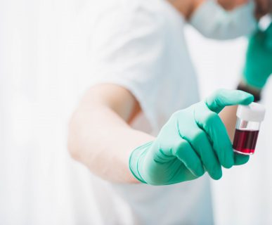 Pielęgniarka ubrana w sterylny strój trzyma w dłoni pobraną próbkę krwi pacjenta do celów diagnostyki i analizy laboratoryjnej. Źródło: 123rf.com