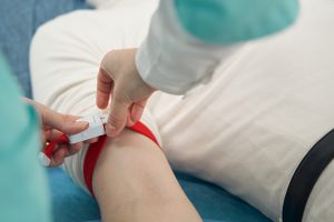 Pacjent zostaje przygotowany do pobrania krwi poprzez założenie opaski uciskowej na rękę przez pielęgniarkę.