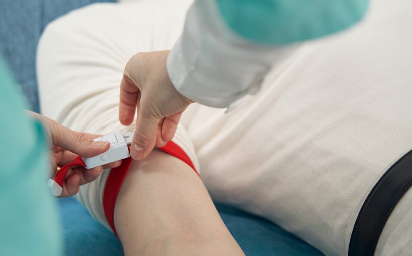 Pacjent zostaje przygotowany do pobrania krwi poprzez założenie opaski uciskowej na rękę przez pielęgniarkę. Źródło: 123rf.com