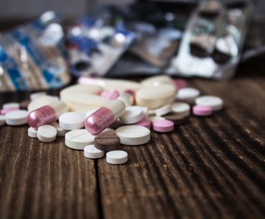 Leki psychoaktywne w formie pigułek rozłożone na drewnianym blacie. /Źródło: 123rf.com
