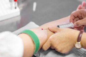 Pielęgniarka pobiera pacjentowi krew z żyły w sterylnych warunkach.