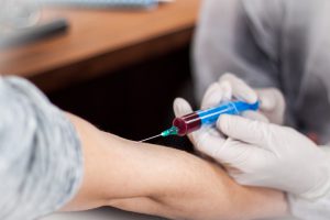 Pielęgniarz pobiera mężczyźnie krew z żyły u ręki aby później przekazać próbkę do analizy laboratoryjnej.