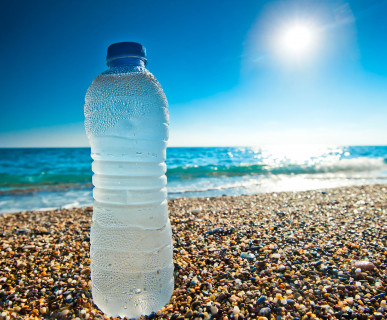Plastikowa butelka napełniona wodą położona na plaży. /Źródło: 123rf.com
