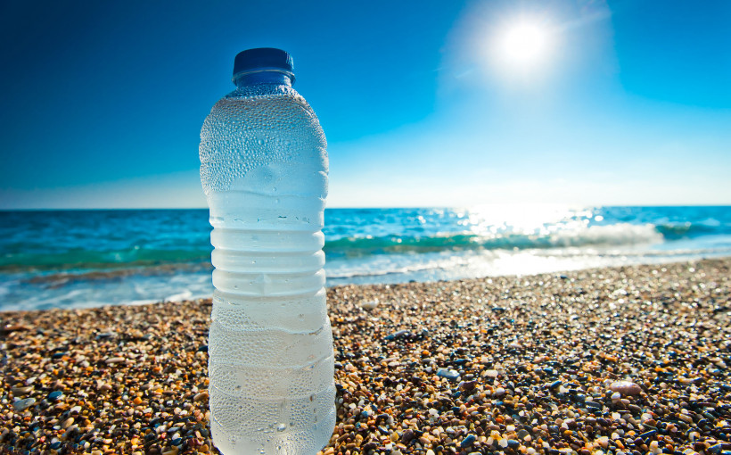 Plastikowa butelka napełniona wodą położona na plaży. /Źródło: 123rf.com