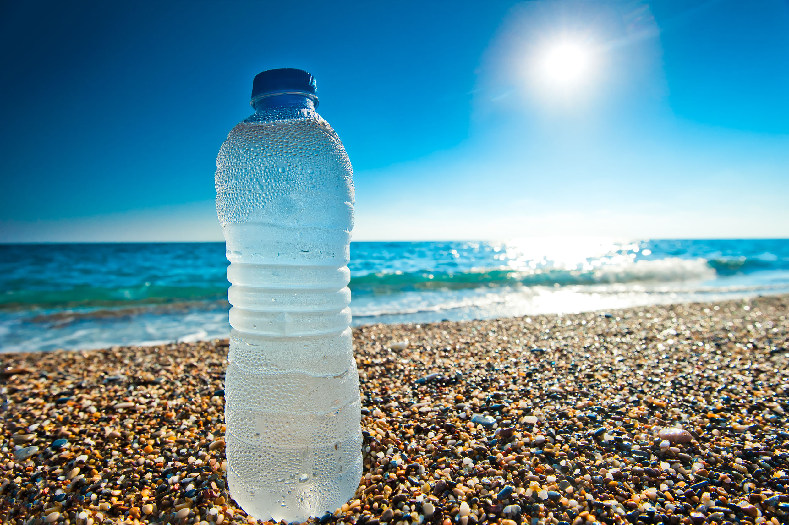 Plastikowa butelka napełniona wodą położona na plaży. /Źródło: 123rf.com