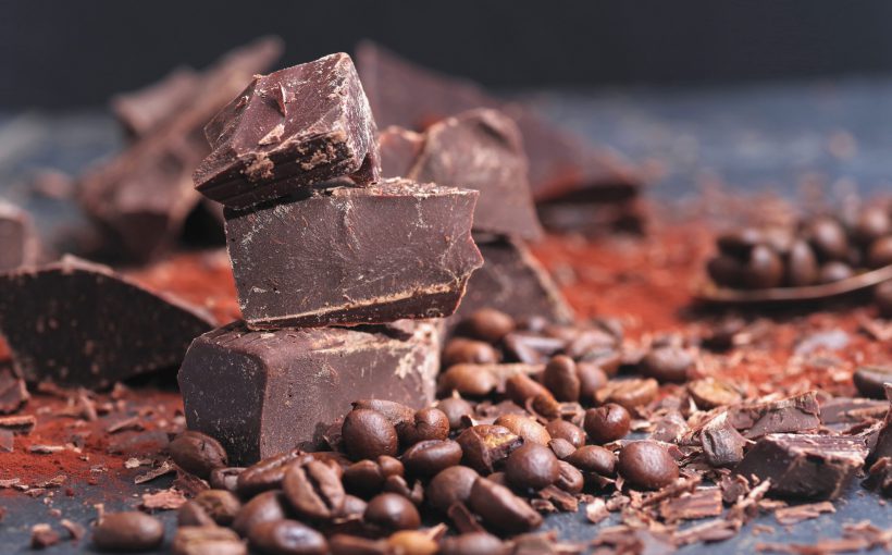 Ziarna kakaowca i kawałki gorzkiej, ciemnej czekolady ułożone na stole. /Źródło: 123rf.com