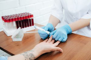 Pielęgniarka pobiera pacjentowi w punkcie pobrań krew z opuszka palca w celu szybkiej diagnozy laboratoryjnej.