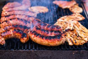 Mięso wieprzowe i kiełbasa na rozżarzonym grillu, z którego unosi się dym. /Źródło: 123rf.com