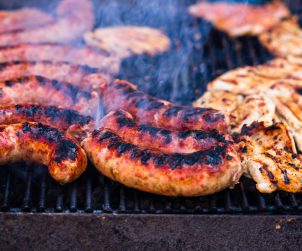 Mięso wieprzowe i kiełbasa na rozżarzonym grillu, z którego unosi się dym. /Źródło: 123rf.com
