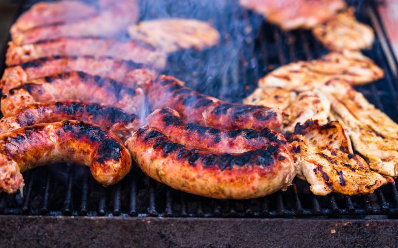 Mięso wieprzowe i kiełbasa na rozżarzonym grillu, z którego unosi się dym. /Źródło: 123rf.com