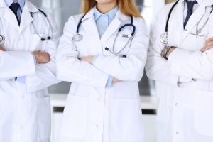 Młodzi lekarze dumnie stoją w fartuchach lekarskich. /Źródło: 123rf.com