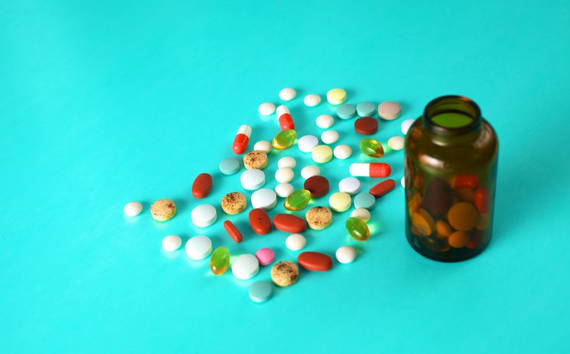 Lekarstwa w formie tabletek wysypane z opakowania na niebieski blat. /Źródło: 123rf.com