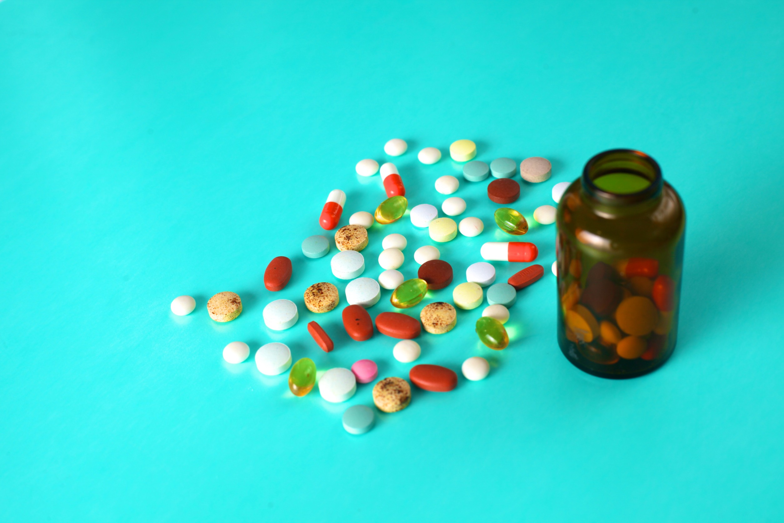 Lekarstwa w formie tabletek wysypane z opakowania na niebieski blat. /Źródło: 123rf.com