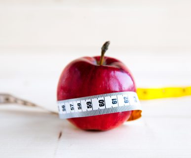 Czerwone jabłko owinięte miarką. Koncepcja zdrowego stylu życia. /Źródło: 123rf.com